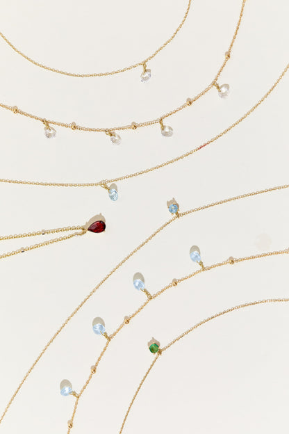 Liabelle 18K Goldkette mit hellblauen Topasen und filigranen Details